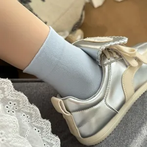Vue détaillée de chaussettes en coton bleu clair associées à des baskets argentées élégantes