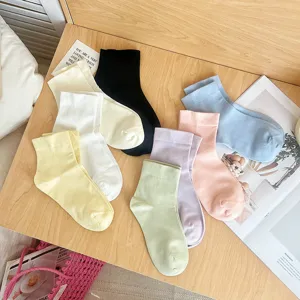 Selection of soft solid color cotton mid-calf socks for women displayed on a wooden surface