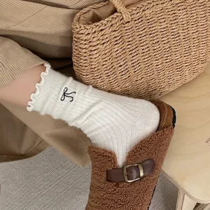 Gros plan détaillé d'une chaussette d'hiver blanche côtelée et volantée à broderie de nœud.