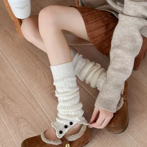 Close-up detail of cozy white knitted leg warmers featuring cute button accents for autumn style.