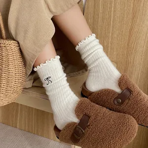 Chaussettes en laine blanche douillettes avec jolis nœuds noirs brodés pour l'automne et l'hiver.