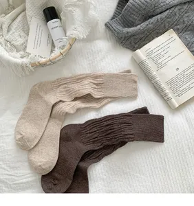 Detailed view of cozy ribbed knit long socks in neutral oatmeal and dark brown colors.