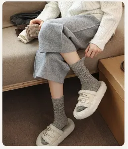 Detail view of thick warm wool cable-knit mid-calf socks worn by model indoors.
