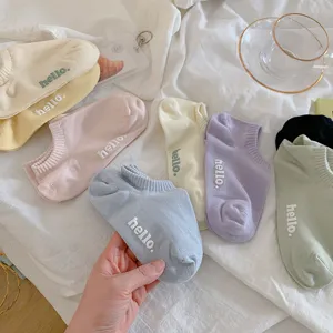 Detailopname van kleurrijke pastel katoenen enkelsokken met hello borduursel op wit.