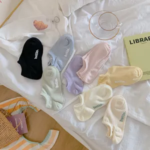 Detail van kleurrijke katoenen enkelsokken met 'hello' borduursel op bed