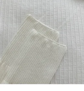 Close up detail of white ribbed knit women socks texture, showcasing fine vertical stripe pattern.