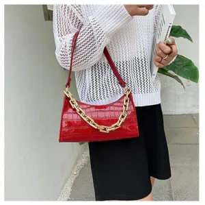 Vista detallada del bolso baguette rojo con textura de cocodrilo y cadena dorada gruesa