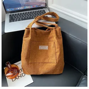 Detailansicht einer braunen Cord-Beuteltasche mit Fashion-Label in Lifestyle-Umgebung