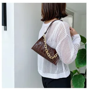 Vista detallada del bolso de hombro marrón con textura de cocodrilo y cadena