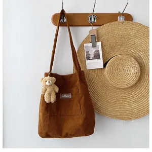 Braune Cord-Einkaufstasche mit Teddybär-Anhänger an einem Wandhaken aus Holz
