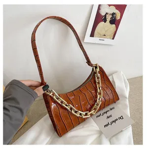 Primer plano de la textura de cocodrilo marrón y la cadena dorada de este bolso de hombro