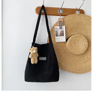 Modische schwarze Cord-Beuteltasche mit süßem Teddybär-Anhänger an der Wandhaken