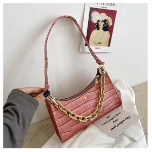 Detalle del bolso de hombro rosa con patrón de cocodrilo y una cadena dorada decorativa