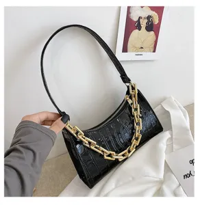 Primer plano de un bolso de hombro negro con textura de cocodrilo y cadena dorada.
