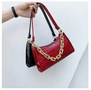 Detalle de los elegantes bolsos rojos y negros con patrón de cocodrilo y cadena dorada