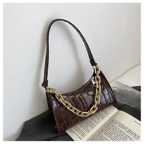 Detalle de bolso de hombro marrón oscuro con grabado de cocodrilo y cadena dorada
