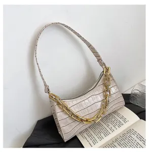 Detalle del bolso baguette crema con diseño de cocodrilo y cadena dorada gruesa.