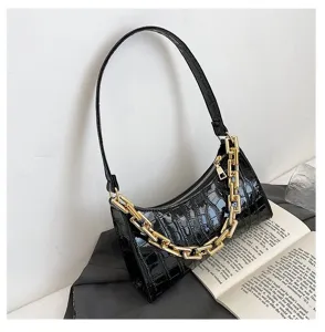 Detalle de bolso de hombro negro efecto cocodrilo con una cadena de eslabones dorada