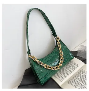 Detalle de la textura de cocodrilo verde y cadena dorada en bolso de hombro de moda