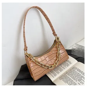 Detalle de bolso de hombro beige con patrón de cocodrilo y cadena dorada