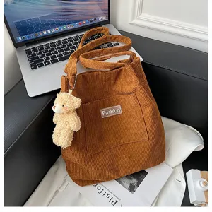 Detailansicht der braunen Cord-Tragetasche mit einem süßen Teddybär-Anhänger als Accessoire