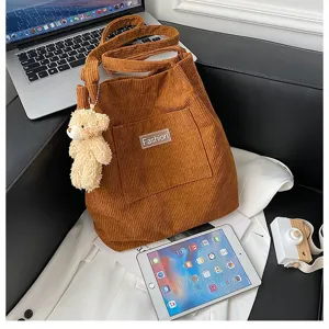 Nahaufnahme der braunen Cord-Eimertasche mit einem niedlichen Plüsch-Teddybär-Anhänger