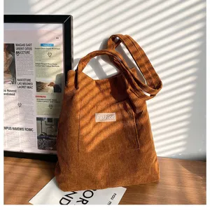 Nahaufnahme einer braunen Cord-Tragetasche mit Fashion-Label in sonniger Umgebung