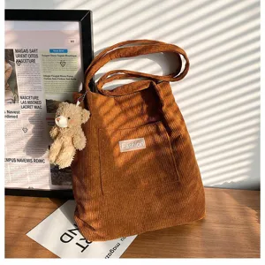 Detail einer braunen Cord-Einkaufstasche mit einem süßen Teddybären-Schlüsselanhänger
