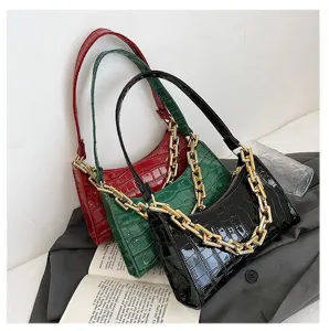 Tres bolsos baguette con efecto cocodrilo en rojo, verde y negro con cadenas doradas gruesas.