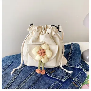 Süße cremefarbene Canvas-Umhängetasche mit großer Plüschblume auf einer Jeansjacke