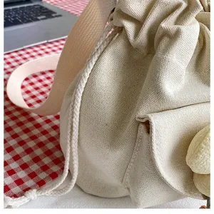 Nahaufnahme einer beige Canvas-Umhängetasche mit Kordelzugtextur und Blumendetail