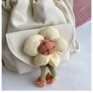 Detailansicht eines niedlichen Plüschblumen-Accessoires an einer cremefarbenen Tasche