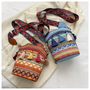 Zwei Eimer-Taschen im Ethno-Stil mit Quasten und bunten bestickten Riemen auf weißem Stoff