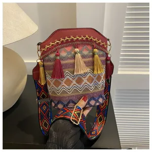 Detailaufnahme einer ethnischen Eimertasche mit bunten Quasten und gewebtem Gurt