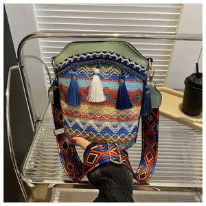 Detailansicht einer farbenfrohen Ethno-Beuteltasche mit dekorativen Quasten und breitem Riemen.