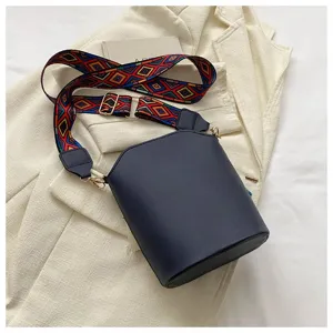 Nahaufnahme einer blauen Eimertasche mit buntem ethnischem geometrischem Gurt