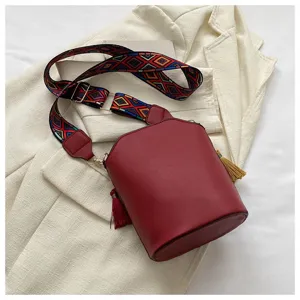 Vintage Ethno-Eimer-Tasche in Burgund mit buntem geometrischem Gurt und Quastendetail