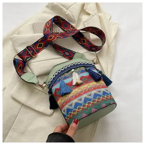Detail der Ethno-Beuteltasche mit bunten Mustern und Quasten auf cremefarbenem Blazer