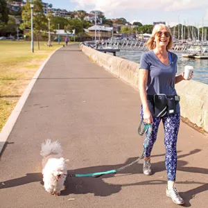 Outdoor lifestyle scene showing a woman using a hands-free dog leash with a waist bag.