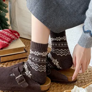 Detailed view of women brown wool winter mid tube socks with classic Fair Isle snowflake pattern.
