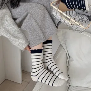 Nahaufnahme von dicken schwarz-weiß gestreiften Wollsocken in gemütlicher Umgebung