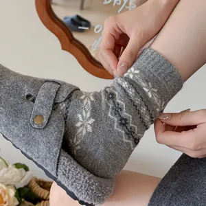Close-up detail of women winter warm grey wool knit mid-tube socks with classic snowflake pattern.