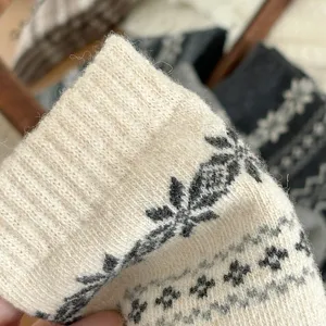 Detailed macro shot of women winter wool socks with Nordic Fair Isle snowflake knit pattern.
