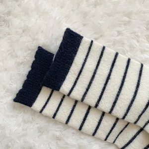 Nahaufnahme von dicken gestreiften Wollsocken mit warmer Strickstruktur auf weißem Teppich