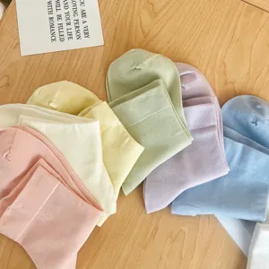 Gros plan détaillé de chaussettes en coton aux tons pastel disposées sur du bois