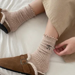 Gros plan de chaussettes douillettes en laine avec broderie de nœud et sabots confortables.
