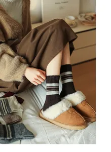 Cozy wool striped mid-tube socks paired with warm plush slippers for autumn and winter home wear.
