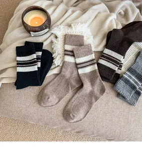 Close up of cozy striped winter socks detailed view on warm knit blanket lifestyle shot.