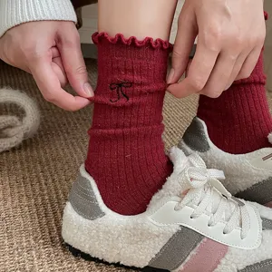 Vue détaillée de chaussettes d'hiver en laine avec broderie de nœud et bordure en dentelle.
