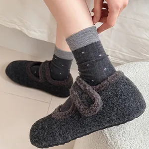 Detailed shot of cozy dark grey fuzzy house shoes and patterned mid-calf socks for winter.